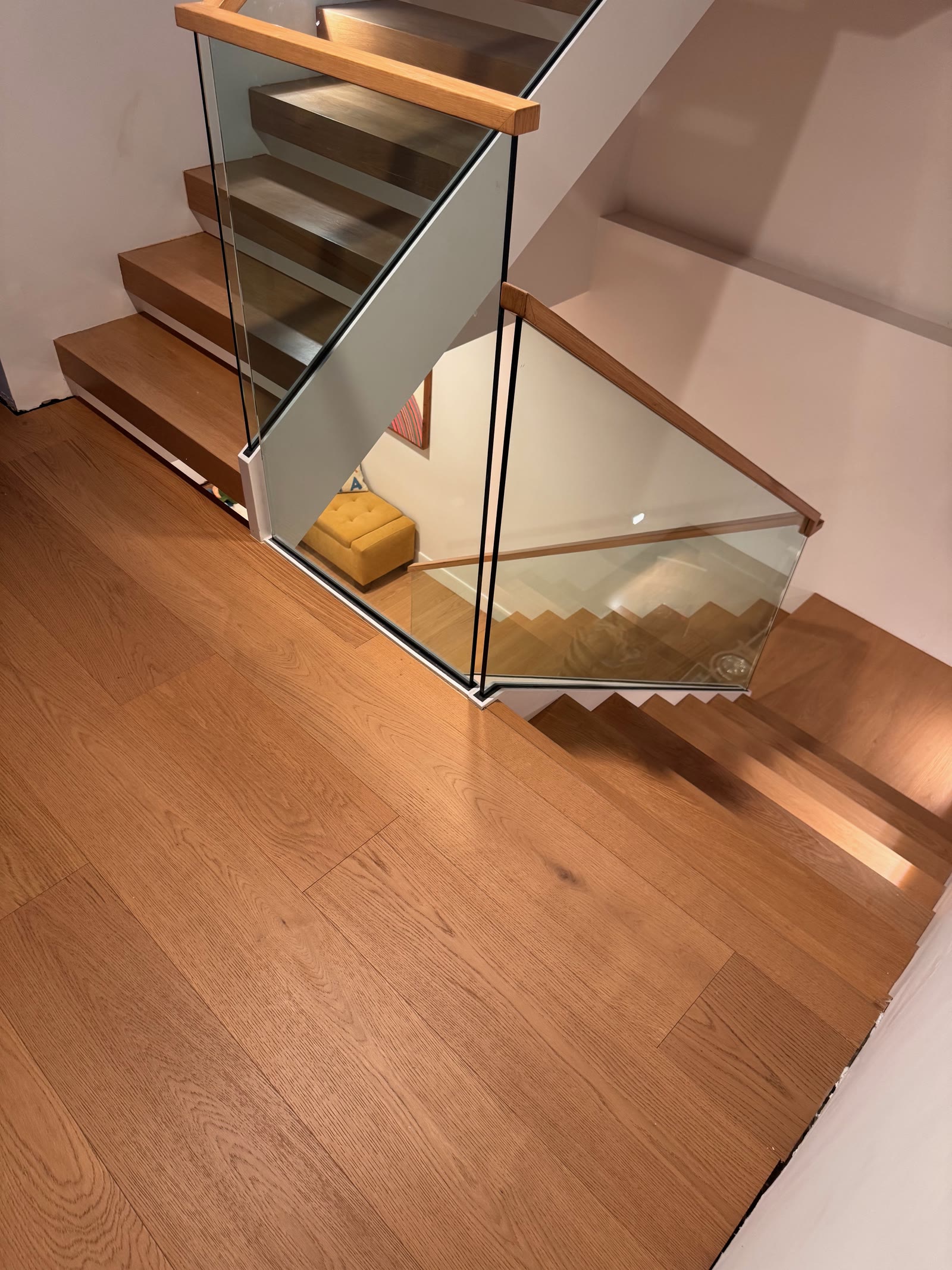 White oak floor at the top of an open-tread staircase with a glass balustrade, La Jolla