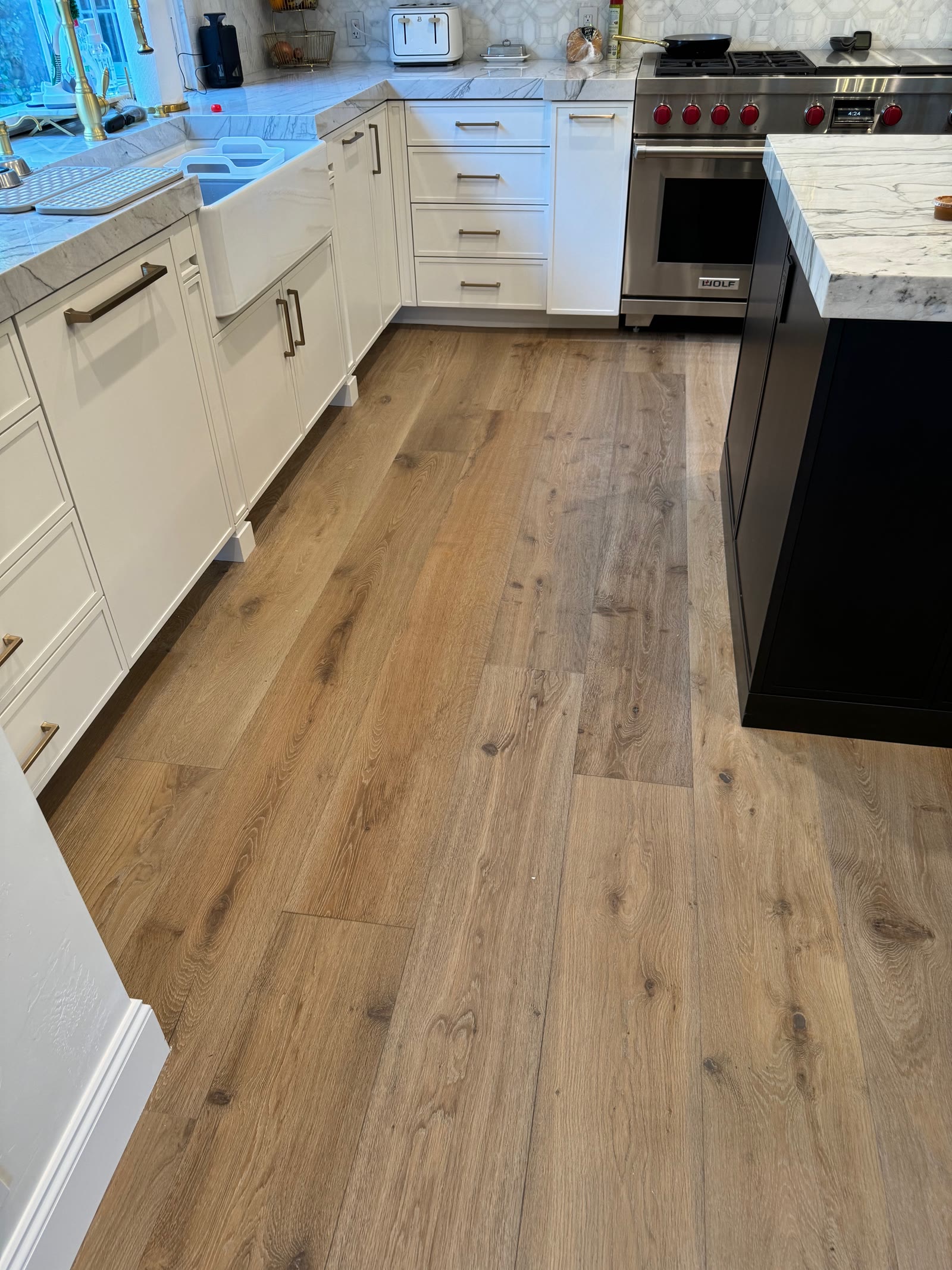 Light wire-brushed white oak plank floor in a Rancho Santa Fe kitchen with marble counters