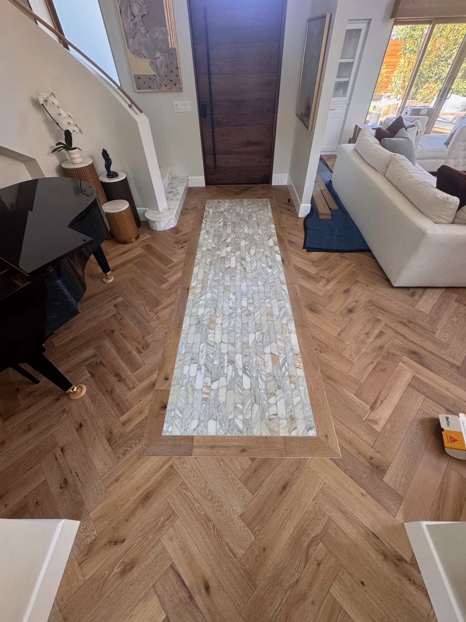 Rancho Santa Fe entry hall in herringbone white oak with a marble mosaic runner leading to a walnut front door