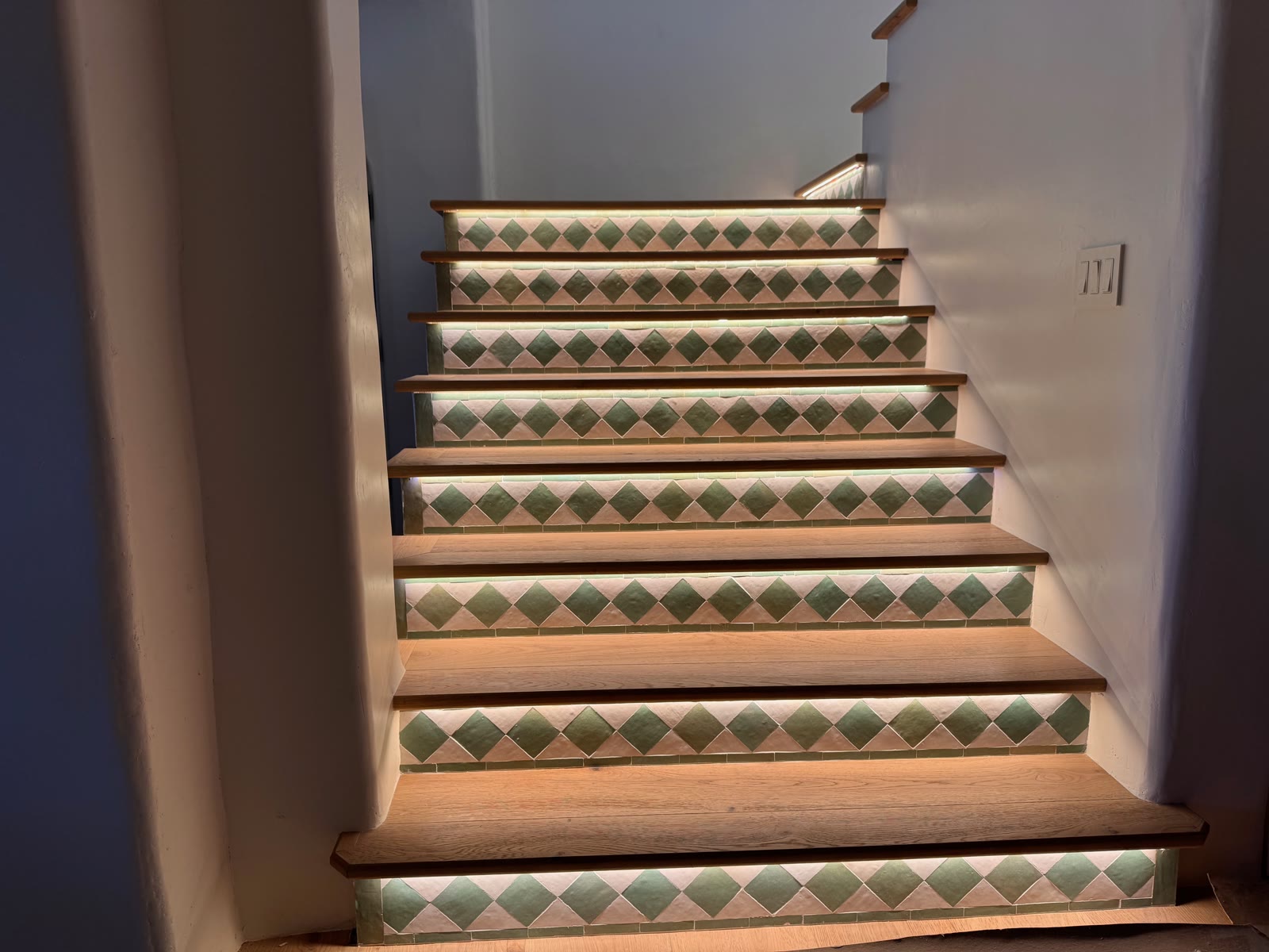 Full flight of oak stairs with green diamond tile risers lit from beneath each tread