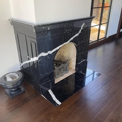 Black marble fireplace surround with dark hardwood flooring