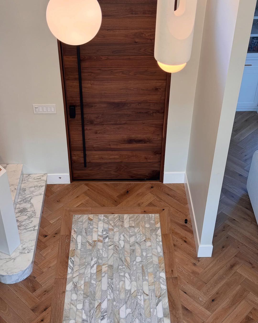 Herringbone pattern flooring with marble inlay